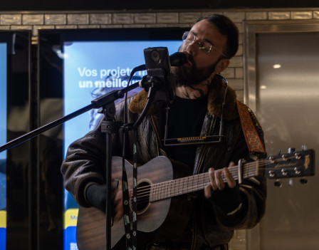 Un musicien dans le métro qui s'accompagne à la guitare, version couleur.