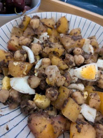 Une salade de pois chiche, oeuf dur, tomate ananas et tapenade. On aperçoit au fond des cerises.