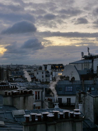 Des toits parisiens, de la fumée qui sort des cheminées, surtout du gris mais aussi un peu d'ocre poudreux du soleil qui se lève derrière.