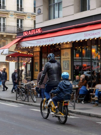 Un homme à vélo avec un garçon sur le porte bagage.