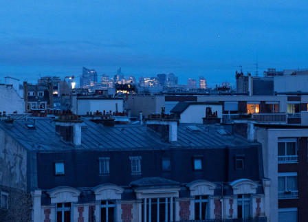 Les lumières de Paris comme points orangés chaleureux dans la lumière bleue de fin de nuit.